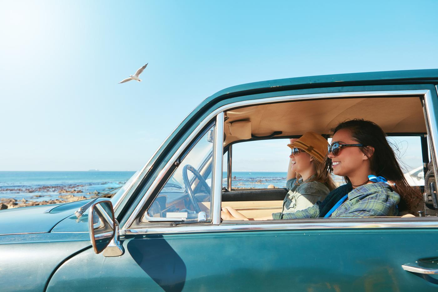 Two friends in a vintage car on a coastal road